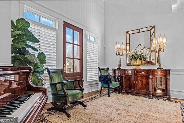 living area featuring a wealth of natural light, an inviting chandelier, a towering ceiling, and hardwood / wood-style flooring