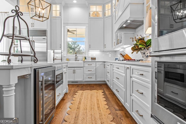 kitchen featuring wine cooler, premium range hood, white cabinetry, and wood-type flooring