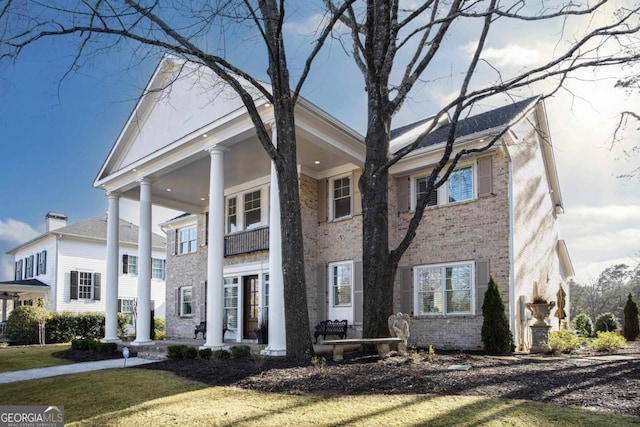 greek revival house featuring a balcony and a front lawn