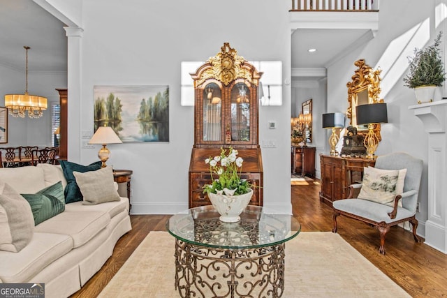 living room featuring a notable chandelier, a towering ceiling, hardwood / wood-style flooring, and crown molding