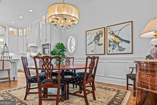 dining space with a wealth of natural light, an inviting chandelier, ornamental molding, and light hardwood / wood-style flooring