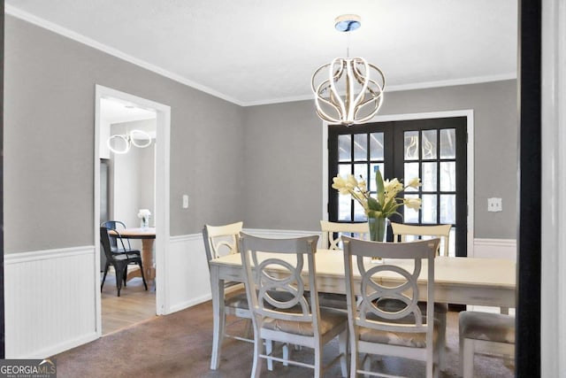 dining space with a chandelier, french doors, carpet floors, and crown molding