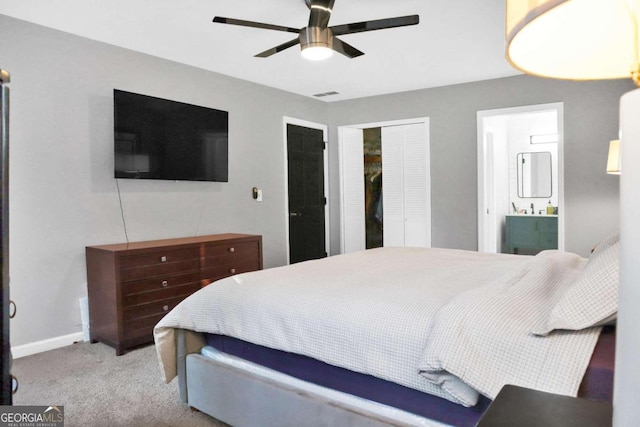 bedroom featuring ceiling fan, ensuite bathroom, and light colored carpet