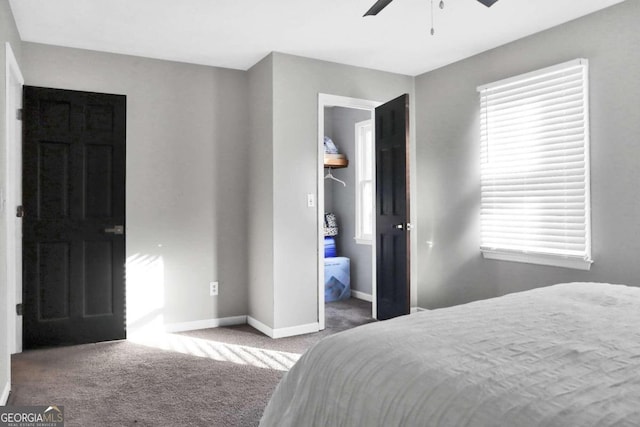 bedroom with ensuite bathroom, a spacious closet, ceiling fan, and dark colored carpet