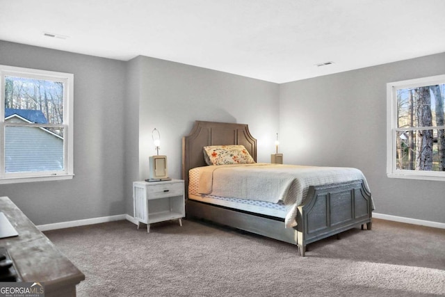 bedroom featuring dark carpet and multiple windows