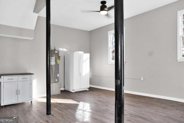 basement with ceiling fan, electric water heater, dark wood-type flooring, and white refrigerator