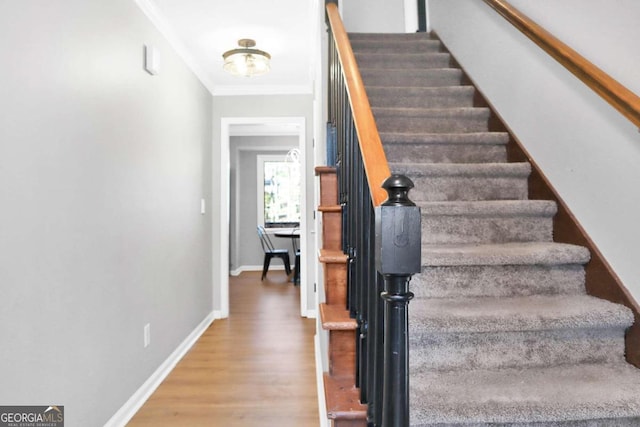 staircase with ornamental molding and wood-type flooring