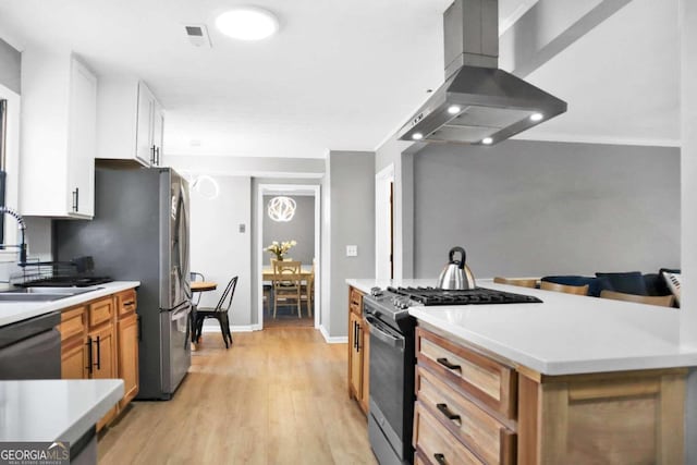 kitchen with white cabinetry, light hardwood / wood-style flooring, range with gas cooktop, island range hood, and sink