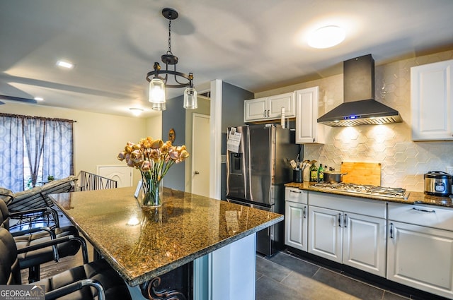 kitchen with tasteful backsplash, pendant lighting, wall chimney range hood, and white cabinetry