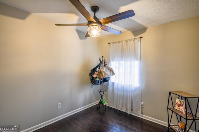 unfurnished room featuring dark wood-type flooring, ceiling fan, and a textured ceiling