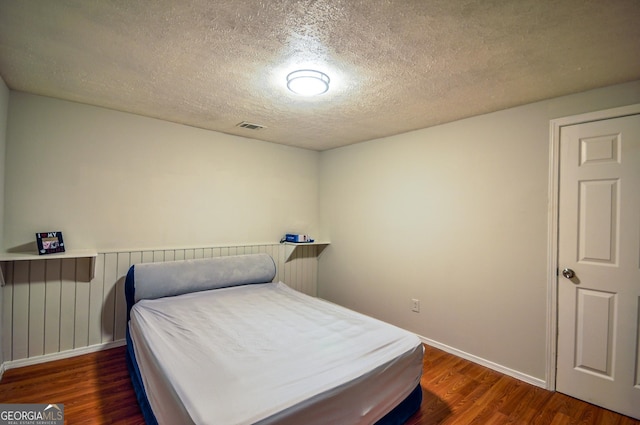 bedroom with dark hardwood / wood-style flooring and a textured ceiling