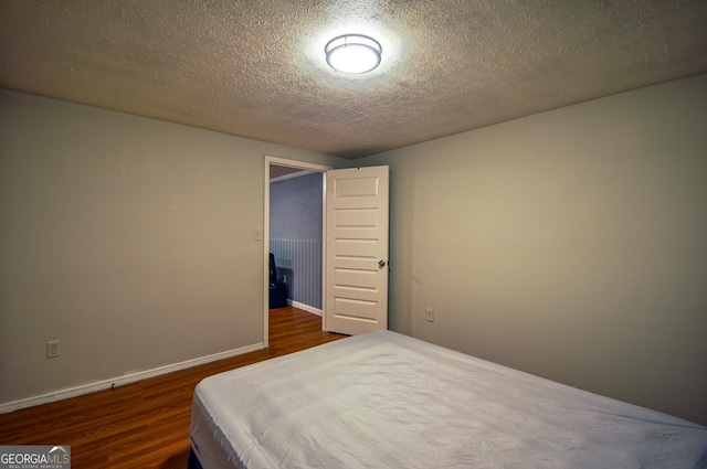 bedroom featuring a textured ceiling and dark wood-type flooring