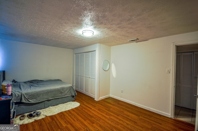 bedroom with a textured ceiling and dark hardwood / wood-style flooring