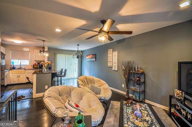 living room featuring ceiling fan with notable chandelier and dark hardwood / wood-style flooring