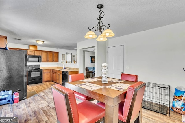 dining area featuring light hardwood / wood-style floors, a textured ceiling, sink, and a chandelier