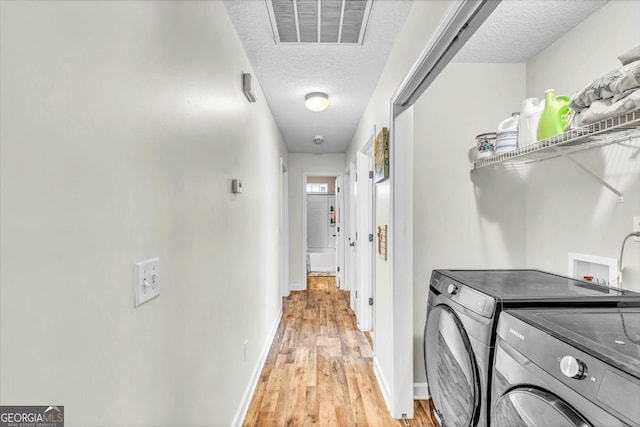 washroom featuring light hardwood / wood-style flooring, washer hookup, separate washer and dryer, and a textured ceiling