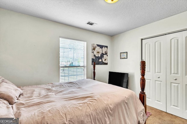 carpeted bedroom featuring a textured ceiling and a closet