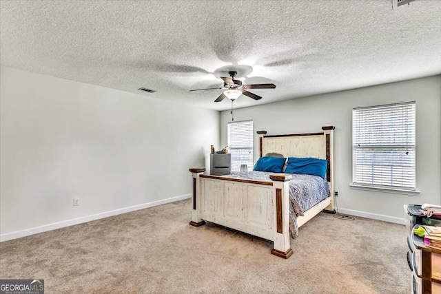 carpeted bedroom featuring ceiling fan, multiple windows, and a textured ceiling