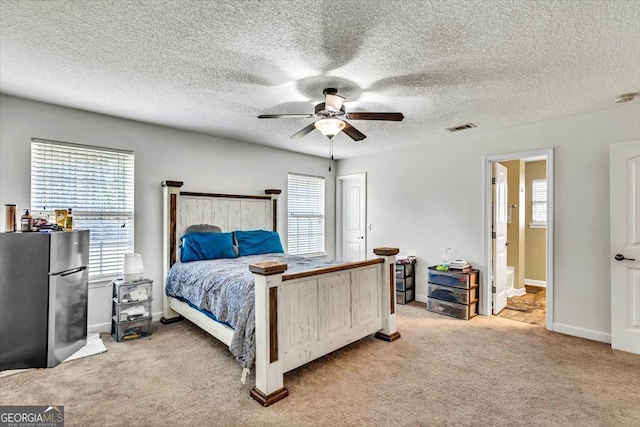 carpeted bedroom featuring stainless steel fridge, ceiling fan, a textured ceiling, and ensuite bath