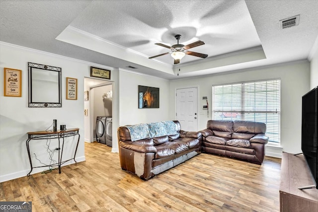 living room featuring light hardwood / wood-style floors, a raised ceiling, independent washer and dryer, and ceiling fan