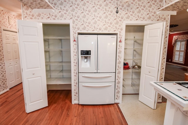 kitchen featuring white fridge with ice dispenser, ornamental molding, and light hardwood / wood-style floors