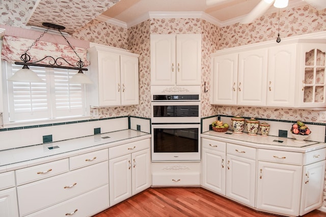 kitchen featuring ceiling fan, crown molding, double wall oven, light hardwood / wood-style floors, and white cabinetry