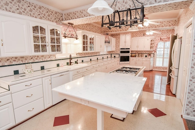 kitchen with white appliances, ceiling fan, ornamental molding, white cabinets, and decorative light fixtures