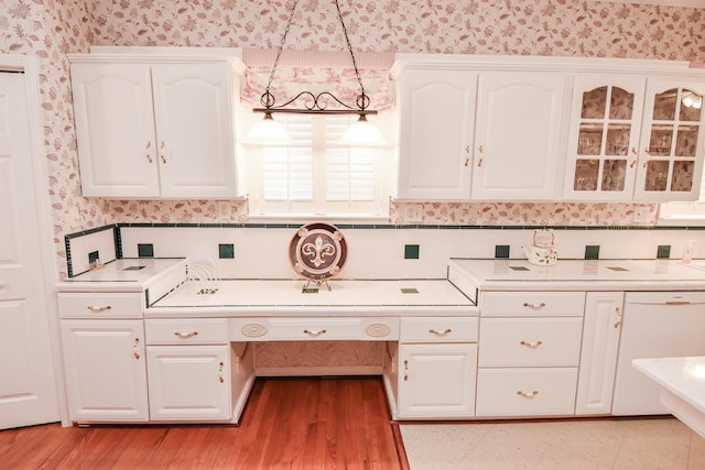 kitchen featuring hanging light fixtures, light wood-type flooring, white cabinets, dishwasher, and tasteful backsplash