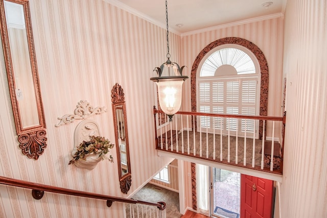 interior space with plenty of natural light, ornamental molding, carpet floors, and a chandelier