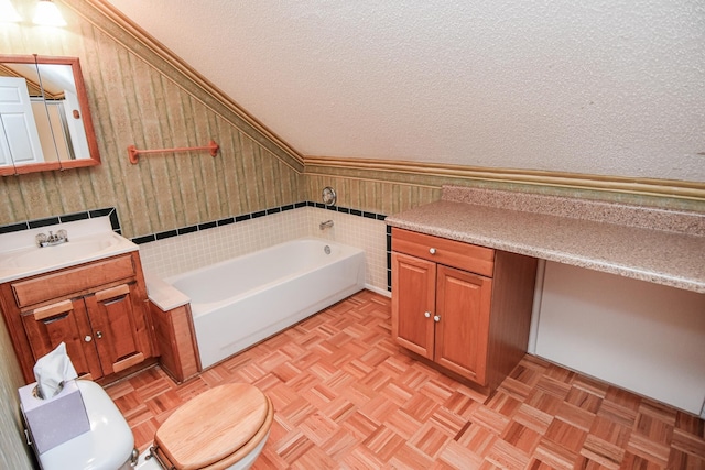 bathroom with toilet, vanity with extensive cabinet space, parquet floors, a textured ceiling, and a bathtub