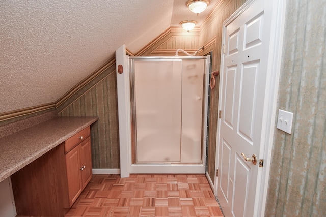 bathroom featuring parquet floors, vanity, a textured ceiling, walk in shower, and vaulted ceiling