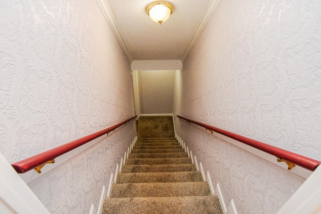 staircase featuring ornamental molding and a textured ceiling