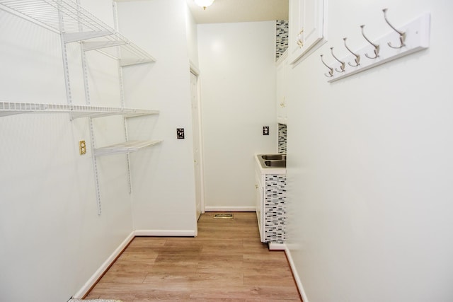 spacious closet with sink and light hardwood / wood-style flooring