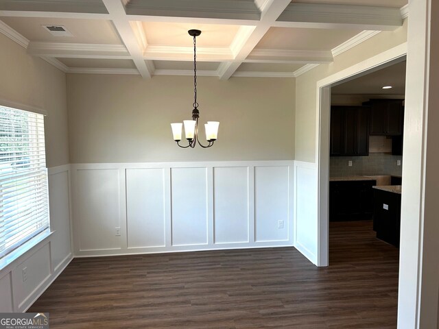 unfurnished dining area with coffered ceiling, dark hardwood / wood-style flooring, ornamental molding, and a notable chandelier