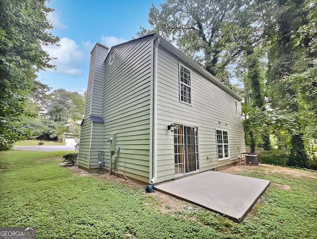 rear view of house featuring a yard, central AC unit, and a patio area