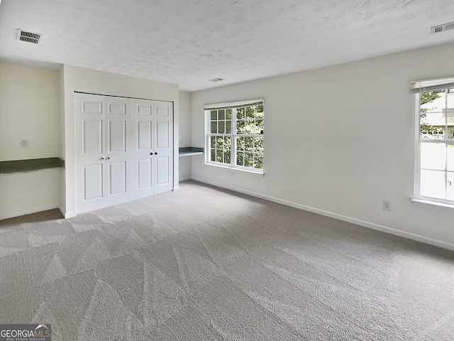 spare room featuring a textured ceiling and carpet