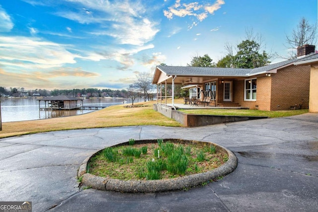 view of property's community featuring a dock, a water view, and a lawn