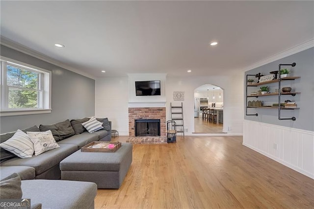 living room featuring crown molding, light hardwood / wood-style floors, and a fireplace