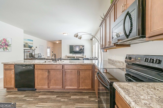 kitchen with light stone counters, sink, kitchen peninsula, dark hardwood / wood-style floors, and black appliances