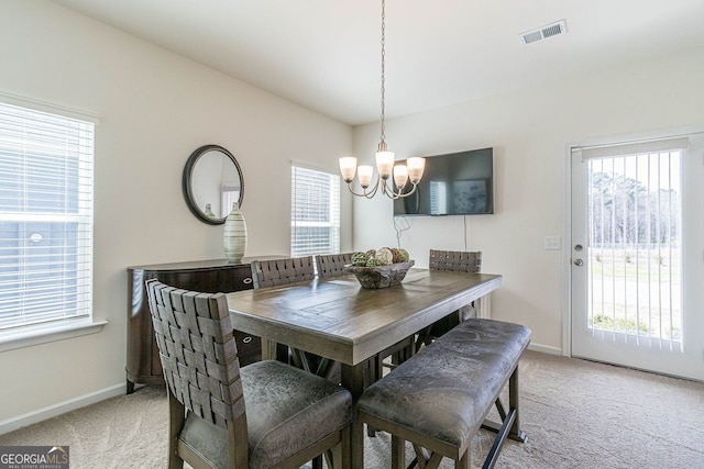 carpeted dining room with a chandelier and plenty of natural light