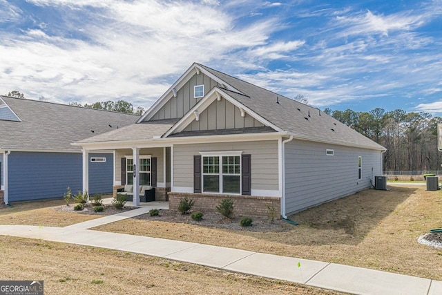 craftsman-style home with covered porch, a front lawn, and central AC