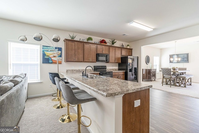 kitchen featuring plenty of natural light, a kitchen breakfast bar, decorative light fixtures, and black appliances