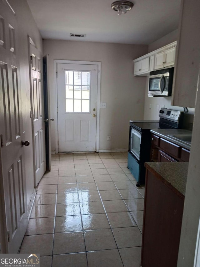 kitchen featuring appliances with stainless steel finishes, white cabinetry, and light tile floors