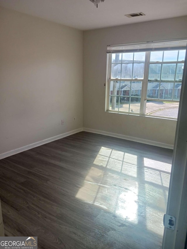 unfurnished room featuring dark hardwood / wood-style flooring and a wealth of natural light