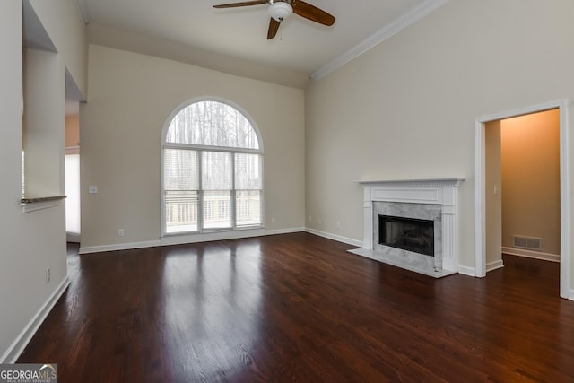 unfurnished living room with a ceiling fan, wood finished floors, baseboards, a fireplace, and ornamental molding