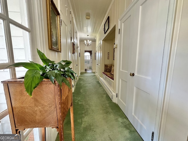 hallway featuring dark carpet and a chandelier