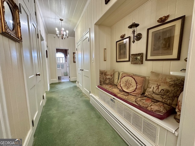 corridor with an inviting chandelier, dark colored carpet, and crown molding