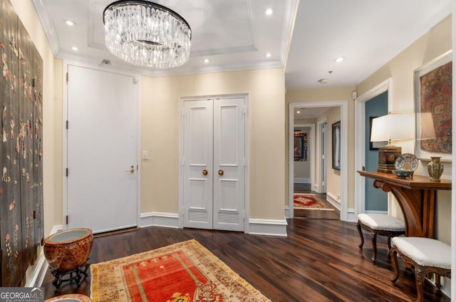 foyer entrance featuring crown molding, a raised ceiling, dark hardwood / wood-style flooring, and an inviting chandelier