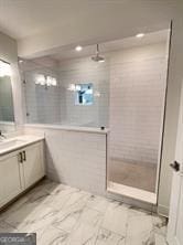 bathroom with a tile shower, large vanity, and tile flooring