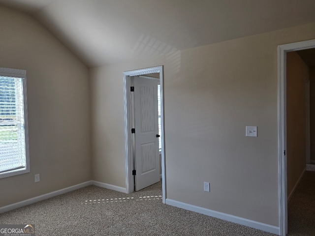 spare room featuring light carpet and lofted ceiling